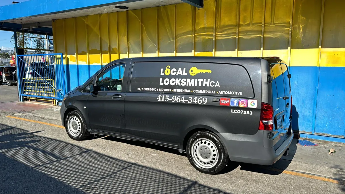 Local Locksmith CA van, black with a yellow key logo, parked at a yellow and blue wall